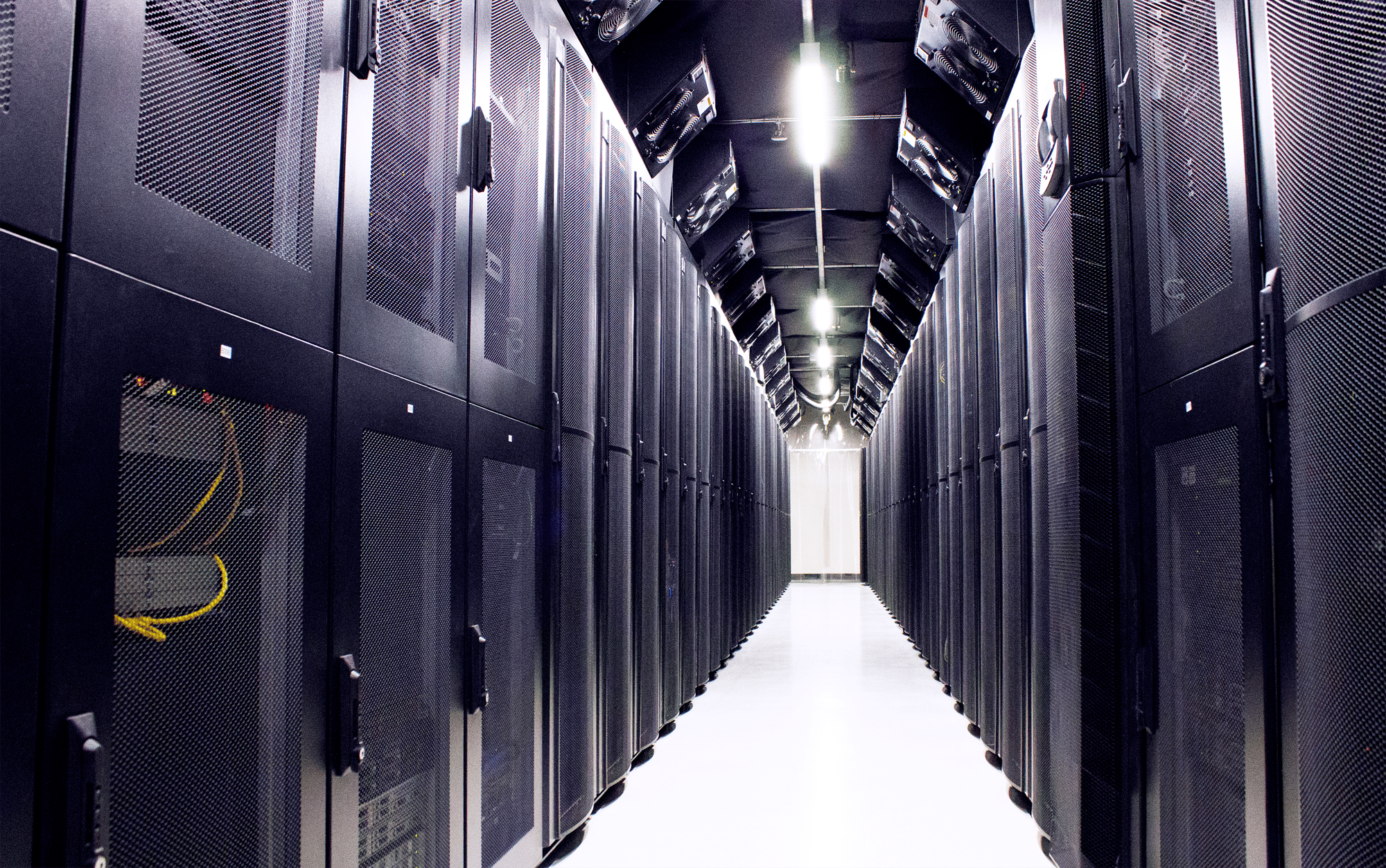A photograph between two rows of black server racks. Found in MTL-5 - our downtown Montreal colocation data center at 1080 Beaver Hall.