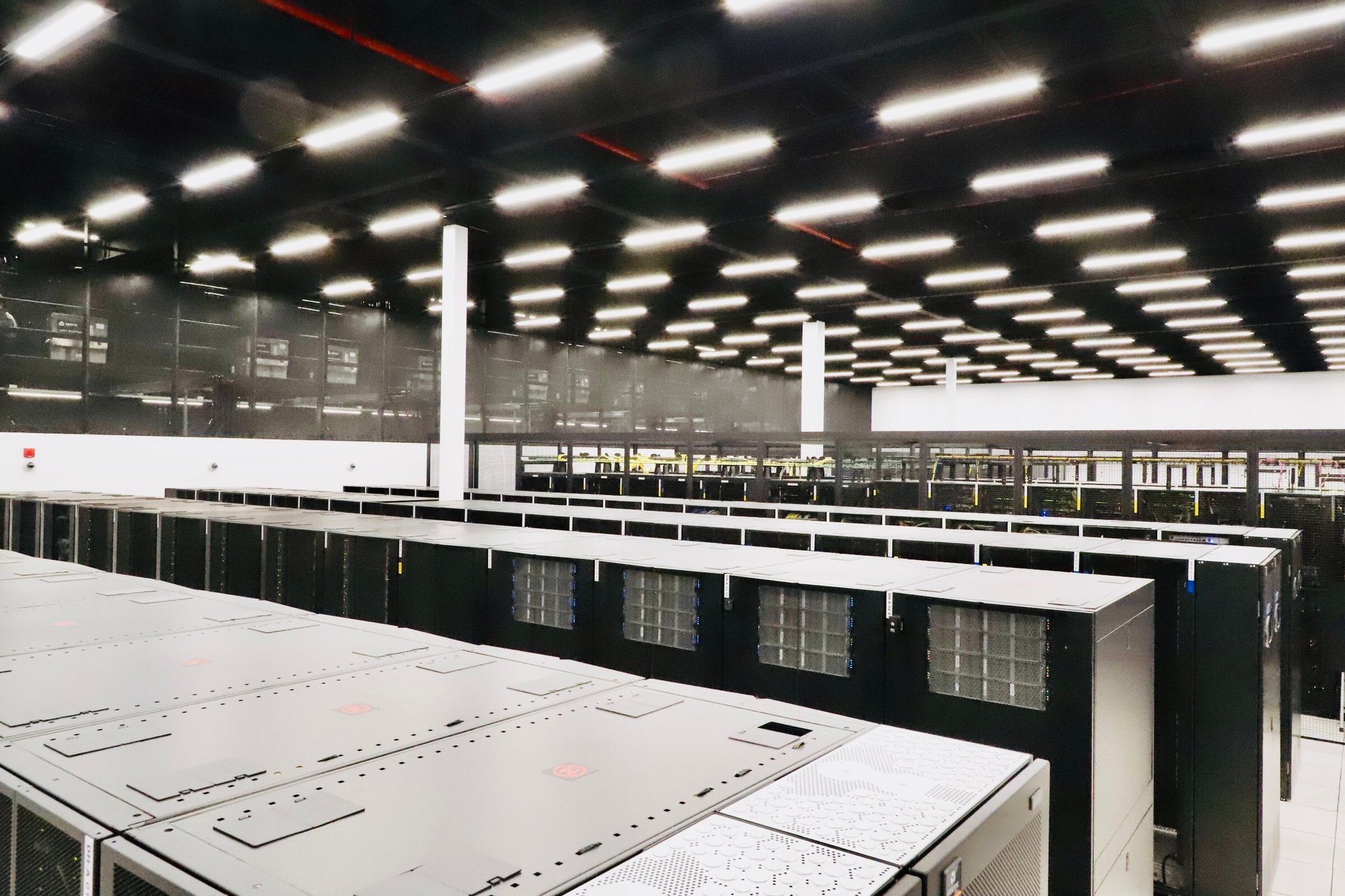 A photograph of a data hall inside of an eStruxture colocation Data Center, showing several rows of black server racks secured within black metal cages.