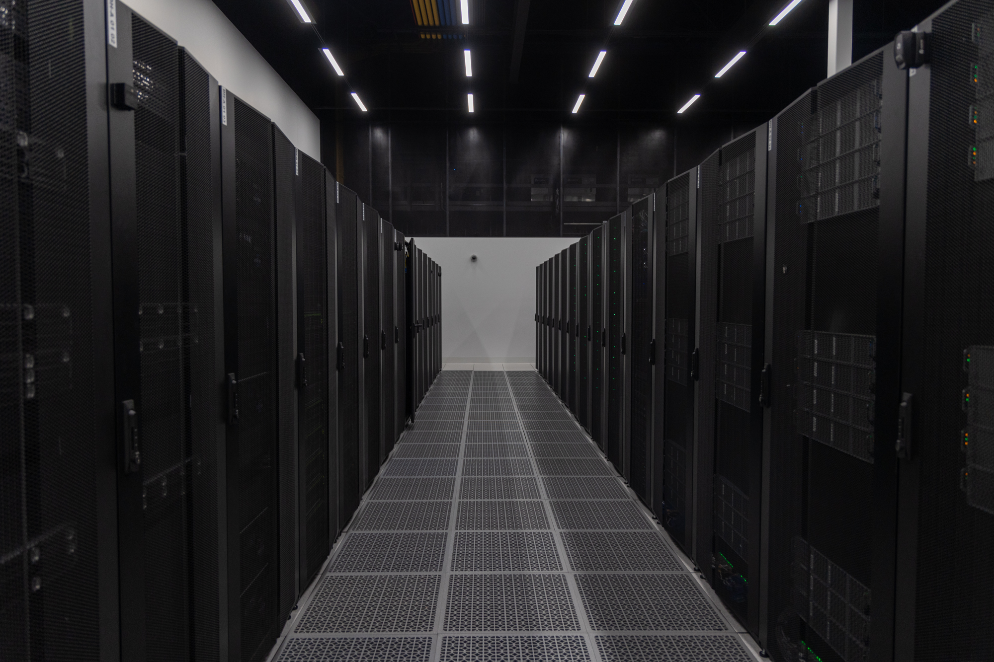 A photograph of a data hall inside of an eStruxture colocation Data Center, showing several rows of black server racks secured within black metal cages.