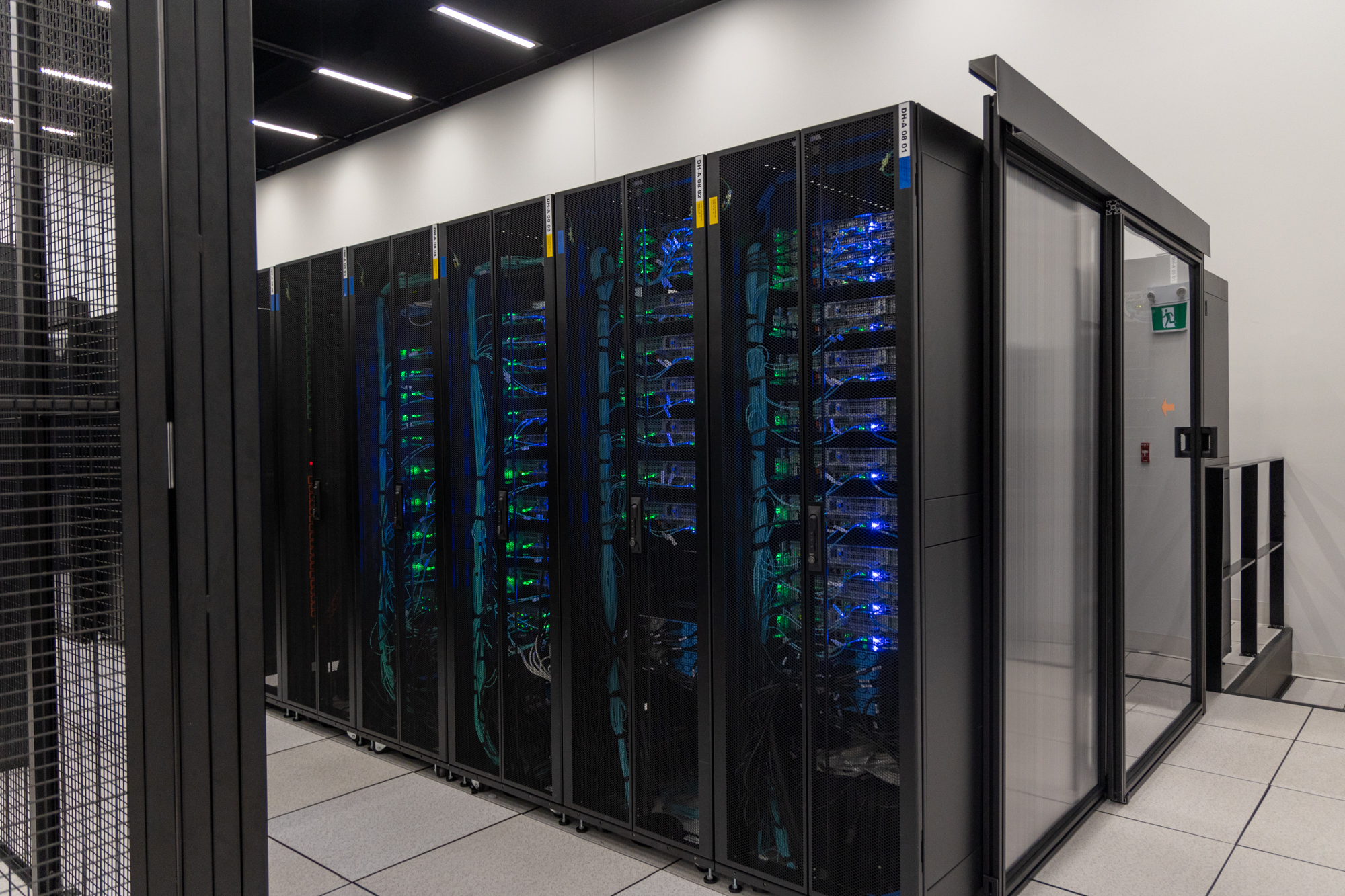 A photograph of a data hall inside of an eStruxture colocation Data Center, showing several rows of black server racks secured within black metal cages. A photograph of a data hall inside of an eStruxture colocation Data Center, showing several rows of black server racks secured within black metal cages.